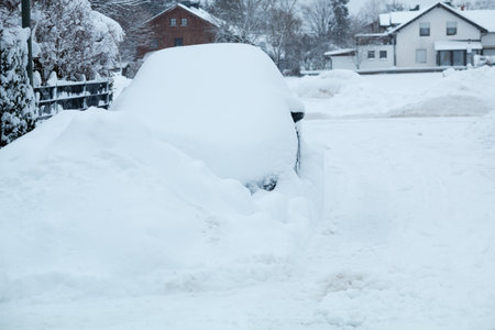 snowbound car beside the street and big snow heap, winter in germanyの写真素材