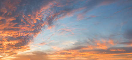 dreamy sunset scenery with pink and orange lighted clouds, blue sky backgroundの写真素材