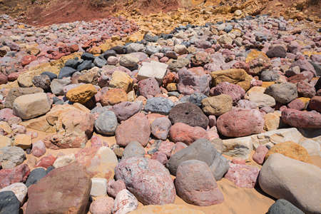 rocky algarve coast, beach with colorful stones, yellow red and greyの写真素材