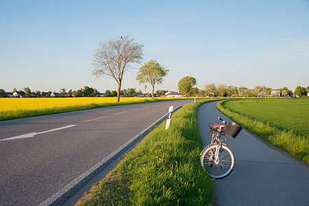 country road and bike way beside, along canola field, village outskirts, upper bavariaの写真素材
