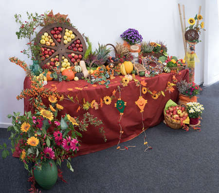 decorative thanksgiving table with fruits and vegetables, wooden wheel and flower vaseの写真素材