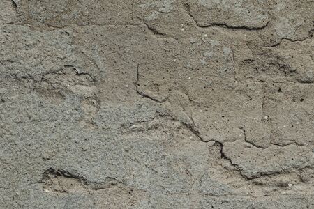 Old ruined and cracked wall made of red bricks with remains of plaster.の写真素材