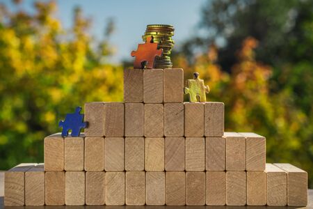 Several puzzles climb to the top of the pyramid made of wooden blocks. The concept of achieving business goals and reaching new levels of promotion.の写真素材