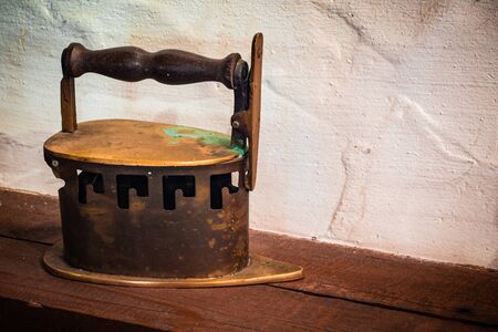 An old iron standing on a wooden countertop against a white wall in an old abandoned house.の写真素材