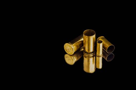 Comparison of sizes of different used bullet shells on a black isolated background with reflection from a tin table top. View of the different caliber cartridges.の写真素材