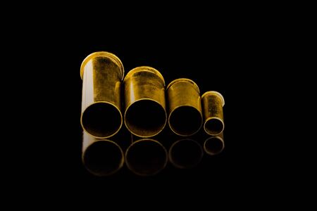 Comparison of sizes of different used bullet shells on a black isolated background with reflection...