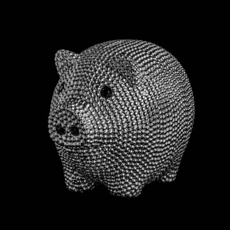 Silver metal piggy bank with black eyes isolated on black background.の写真素材