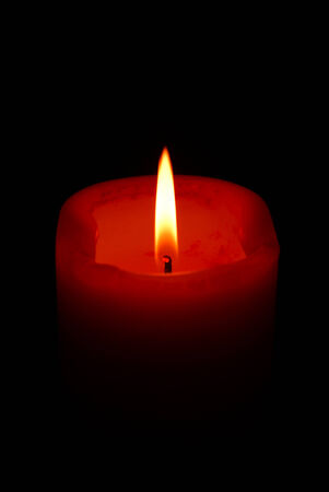 A single orange burning candle isolated on blackの写真素材