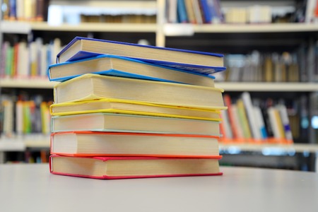 Close up of colorful books on the table. Bookshelves in the background.の写真素材