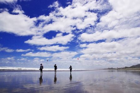 View of beautiful beach and blue sky. Three people are walking on the beach.の写真素材