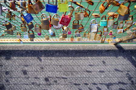 Close up of a lot of love lock on the railing. Blurred pathway in the background. Love lasts...