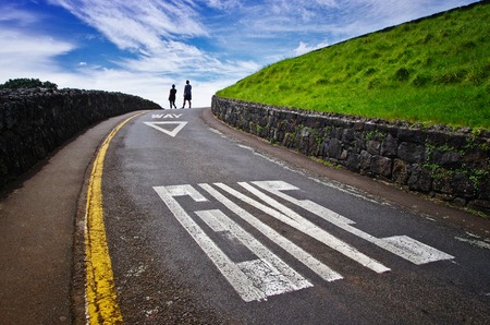 Close up of big sign on the road. Give way concept. Blue sky and two people walking in the background. Transportation safety.の写真素材