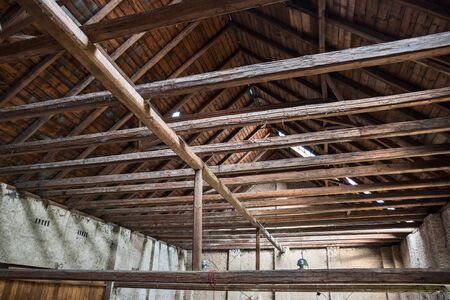 Aged beams in an old barn. Old roof achitecture detail. Wooden timbers. 