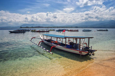 View of wooden fishing boat. Beautiful clear water in the ocean, blue sky in the background.の写真素材