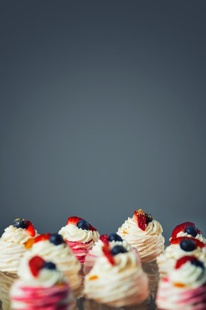 Close up of mini Pavlova cakes. Meringue with cream topping and fruit. Composition with blank space for a text.の写真素材