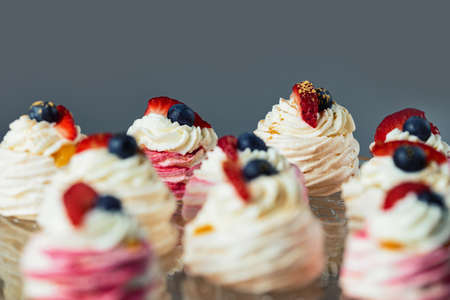 Close up of mini Pavlova cakes. Meringue with cream topping and fruit.の写真素材