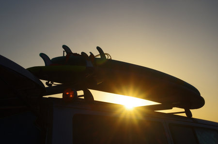 Travel in a van and surf. Surf on the van. Surf silhouette in the sunset. Surfing concept.