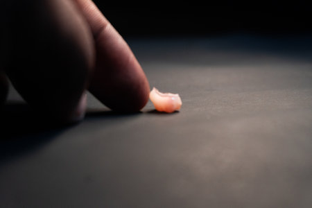Close up view of a human hand squeezing a piece of plastic on a black backgroundの写真素材