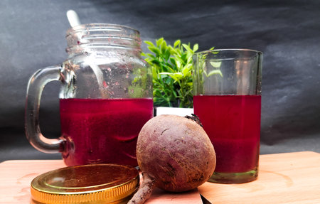 beetroot juice in a glass and a jar on a black background