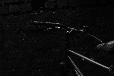 Black and white image of a bicycle on a black wall background.の写真素材