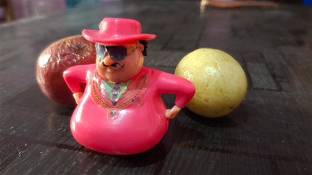 Clay doll with red hat and sunglasses sitting on the table