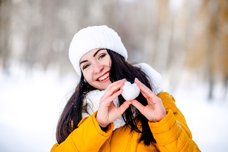 Heart of snow in the hands of a girl. Winter on the street.