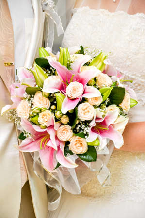 Beautiful wedding bouquet in hands of the bride. Roses and liliesの写真素材