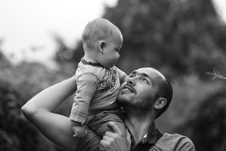 child sits on dad's shoulder and smiling. black and white a photoの写真素材