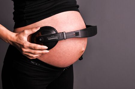 belly of pregnant women and headphones, isolated on black. Studioの写真素材