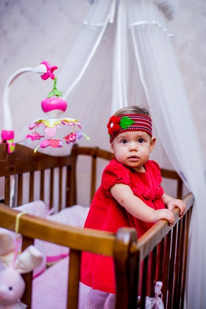 little girl stands in her crib.の写真素材
