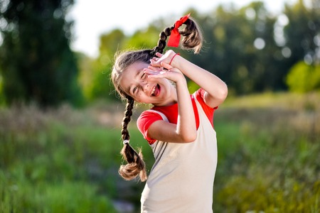 A funny cute outdoor portrait of a little girl sticking her tongue out.の写真素材
