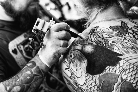the process of creating a tattoo on the back of a girl. Professional tattoo. Carp Fish tattoo. black and whiteの写真素材