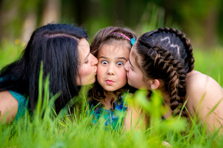 Picture of young mother hugging two little children, closeup portrait of happy family, cute brunette female with daughter and son outdoor in spring time, smiling faces, happiness and love conceptの写真素材