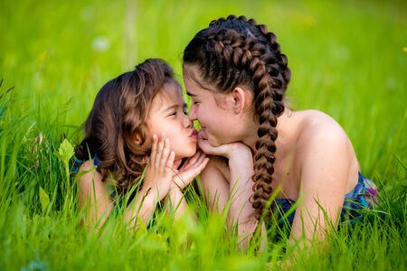 Two sisters lying on the grass and cute smile. Summerの写真素材