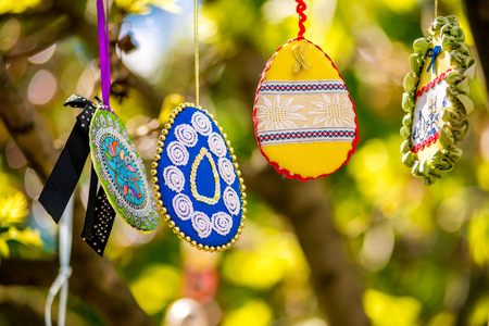 Several Easter colored eggs hanging on a tree branch color sunny spring day. Easter