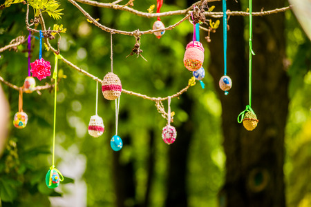 Several Easter colored eggs hanging on a tree branch color sunny spring day. Easter