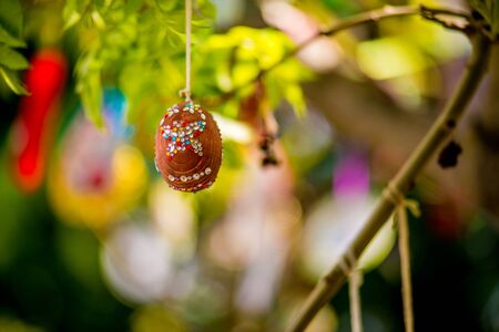 Several Easter colored eggs hanging on a tree branch color sunny spring day. Easter