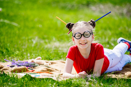 Portrait of a funny  little girl in  glasses. Girl lies on the grassの写真素材