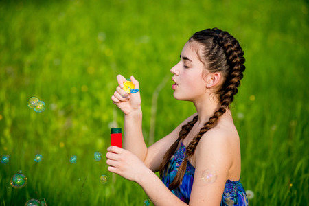 Little girls blow bubbles sitting on the grass. Two sisters