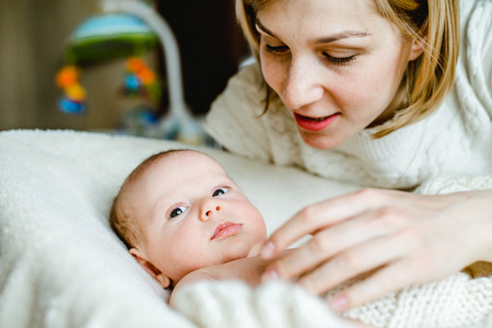 Portrait of happy mother and baby at home. The child is 2 months