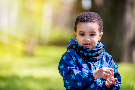 cute happy little boy lying in green grass on spring. black boyの写真素材