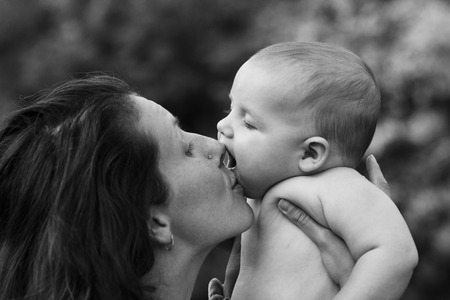 Mother embraces and kisses his little son on natureの写真素材