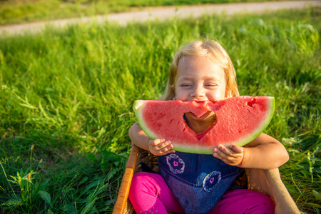 Happy child eating watermelon. Girl having picnic in autumn parkの写真素材
