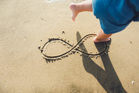 infinity symbol written on Sand on the beach, ocean