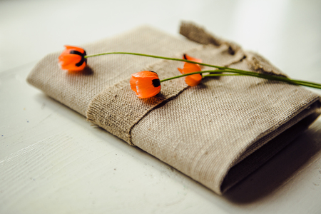 Red poppies lie on the book. The book is wrapped in a linen clothの写真素材