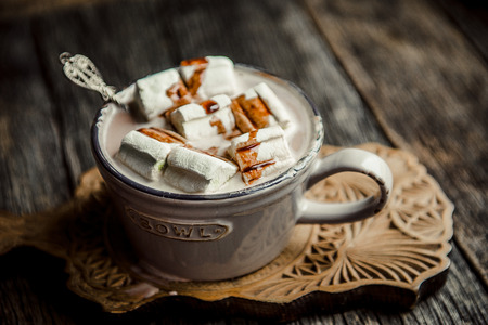 Cup of hot cocoa with marshmallow on cutting board, wooden table backgroundの写真素材