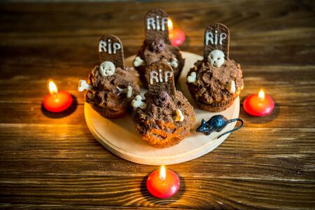 Halloween cupcakes with tombstone cake topper and candle on an old wooden tableの写真素材