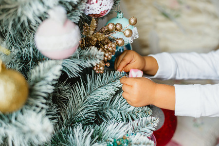 Little girl decorating Christmas tree with glass ballsの写真素材