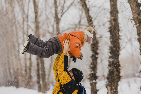 Young father playing with his baby in a snowy park.の写真素材
