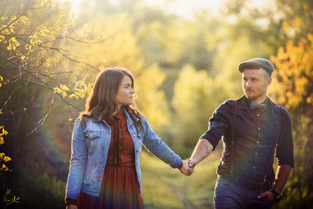 Stunning, young, caucasian couple walking and holding hands at Summer in park